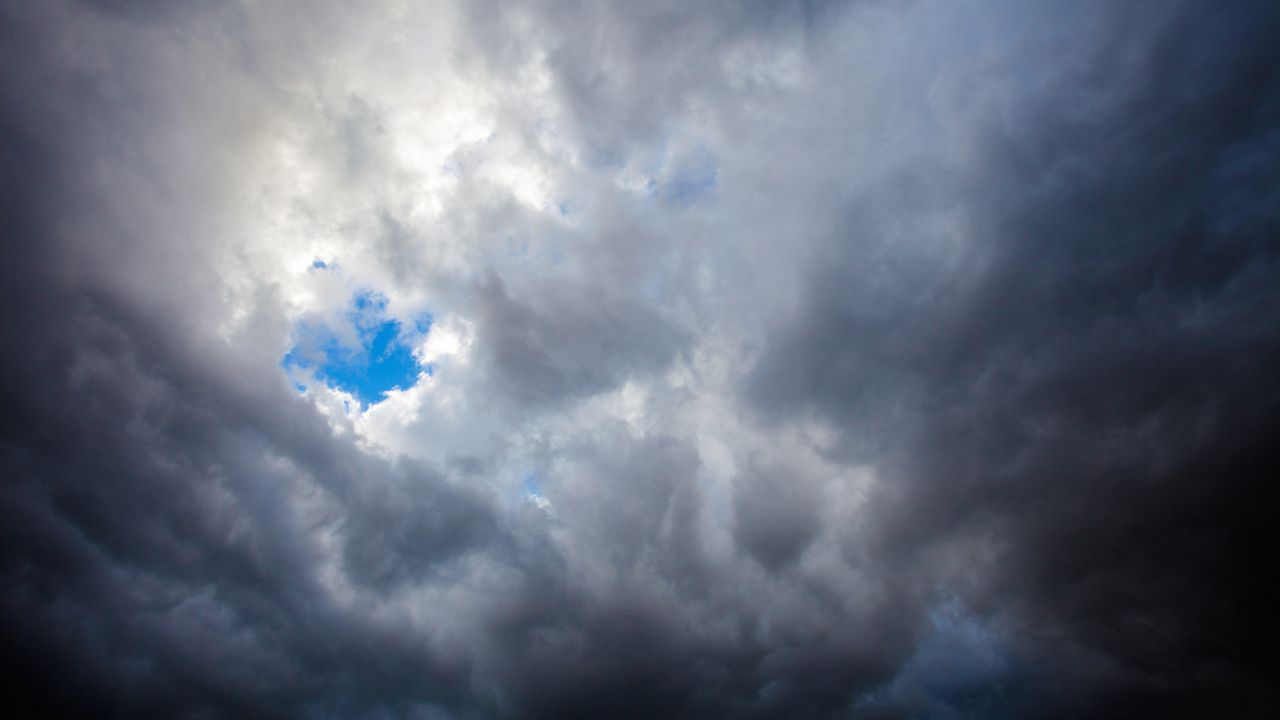 6 un cielo cubierto de nubes grises con una apertura que deja ver el cielo azul y algunas nubes blancas y luminosas