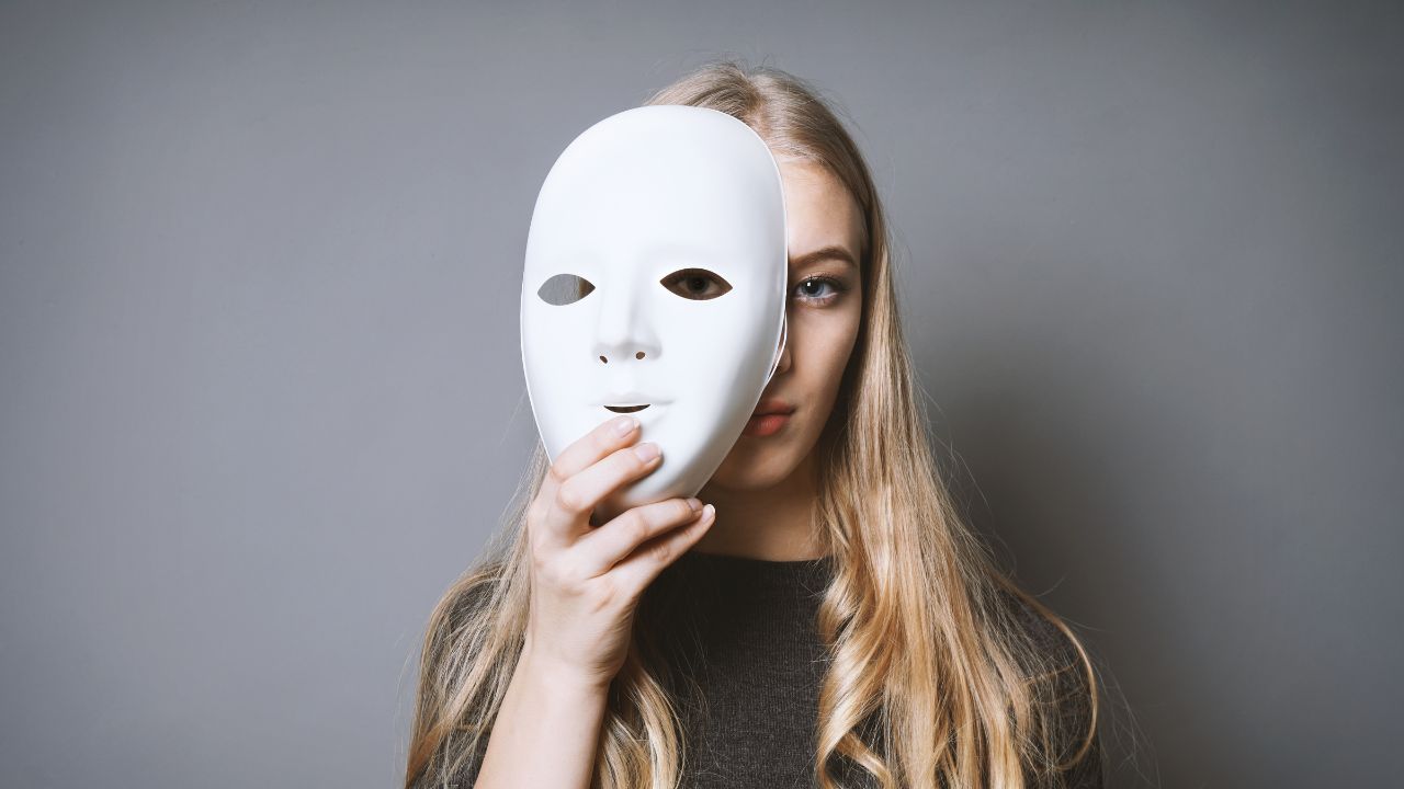 CNV ver al ser humano una mujer sostiene una máscara frente a su cara, mostrando solo una pequeña parte